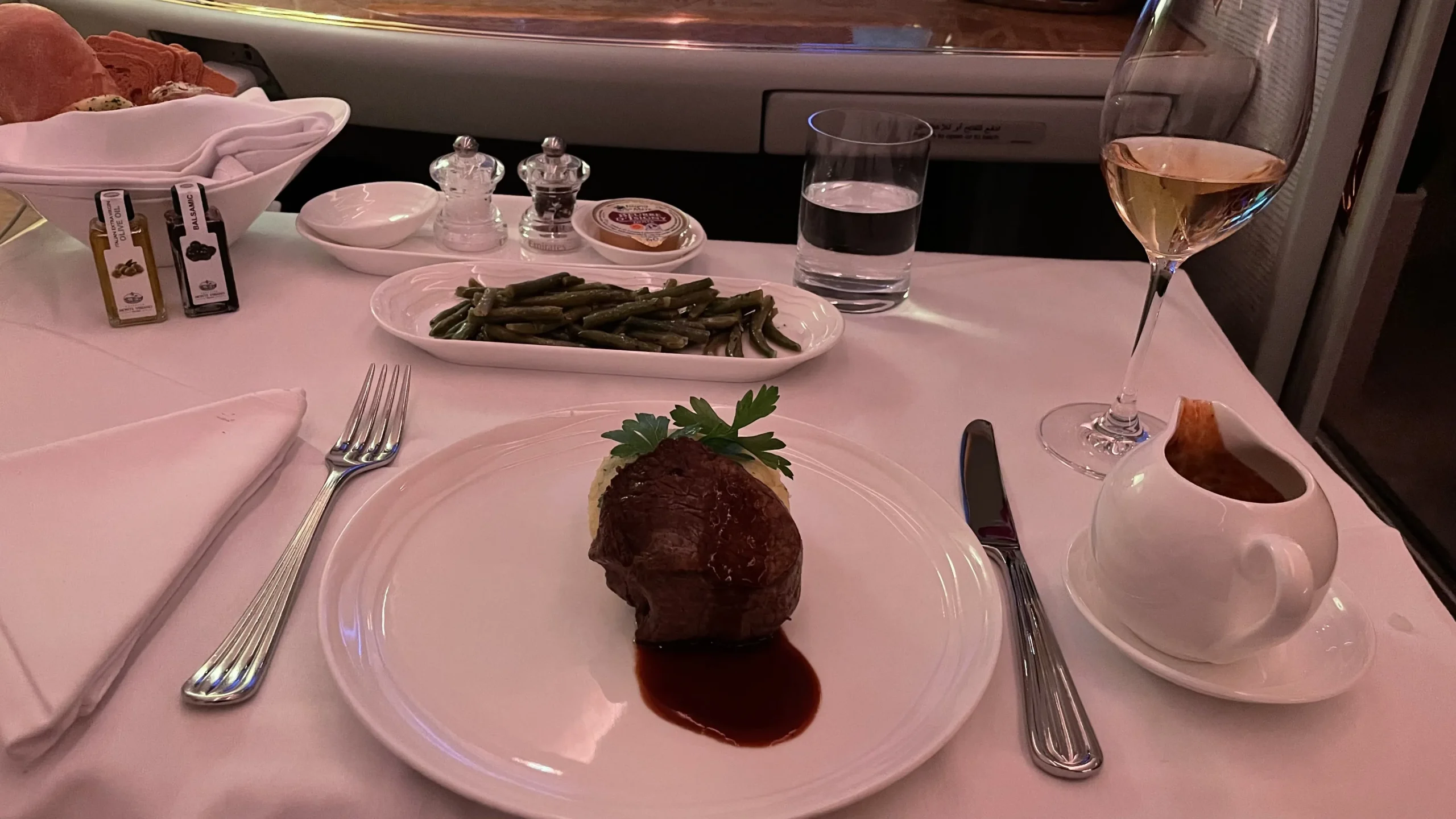 A perfectly cooked medium-rare steak served with vegetables on fine china in an airplane cabin.
