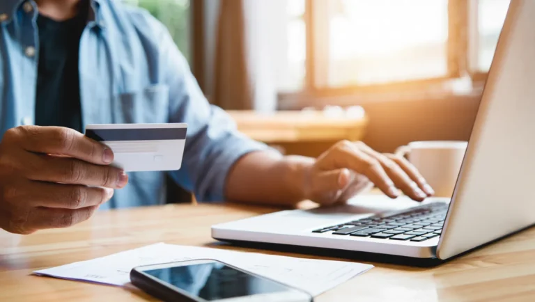 Person holding a secured credit card while reviewing finances at home, illustrating how secured cards help rebuild credit.