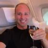 Smiling traveler relaxing in Emirates First Class seat with glass of champagne