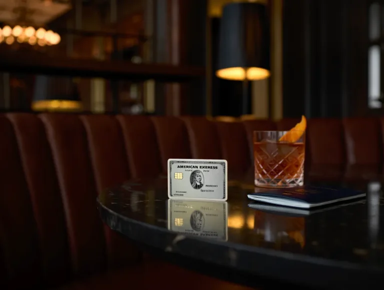 American Express Platinum Card placed on table with cocktail and passport in luxury lounge