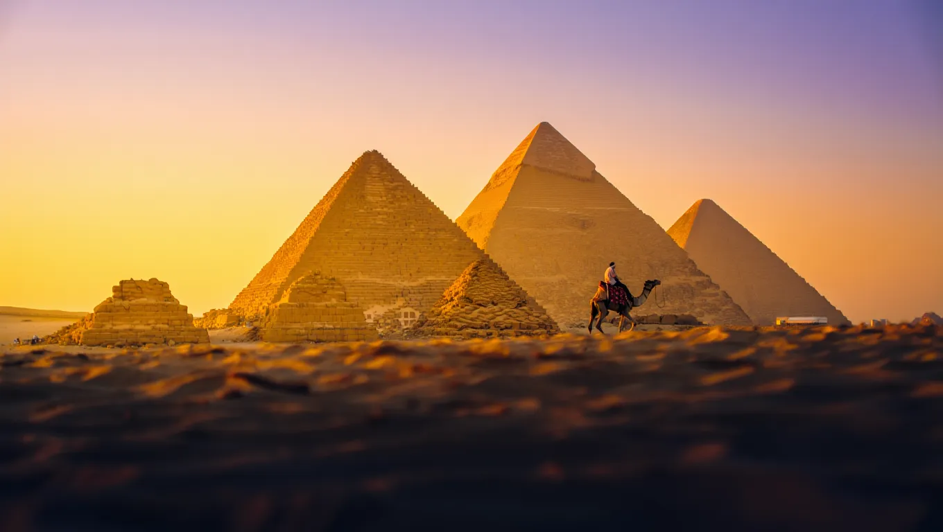 Great Pyramids of Giza in Egypt at sunset with camel rider in the foreground