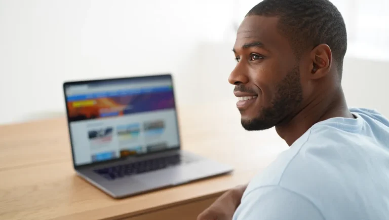 A man in his 30s thoughtfully considers his strategy for navigating airline dynamic pricing on his laptop to find the best award flight.