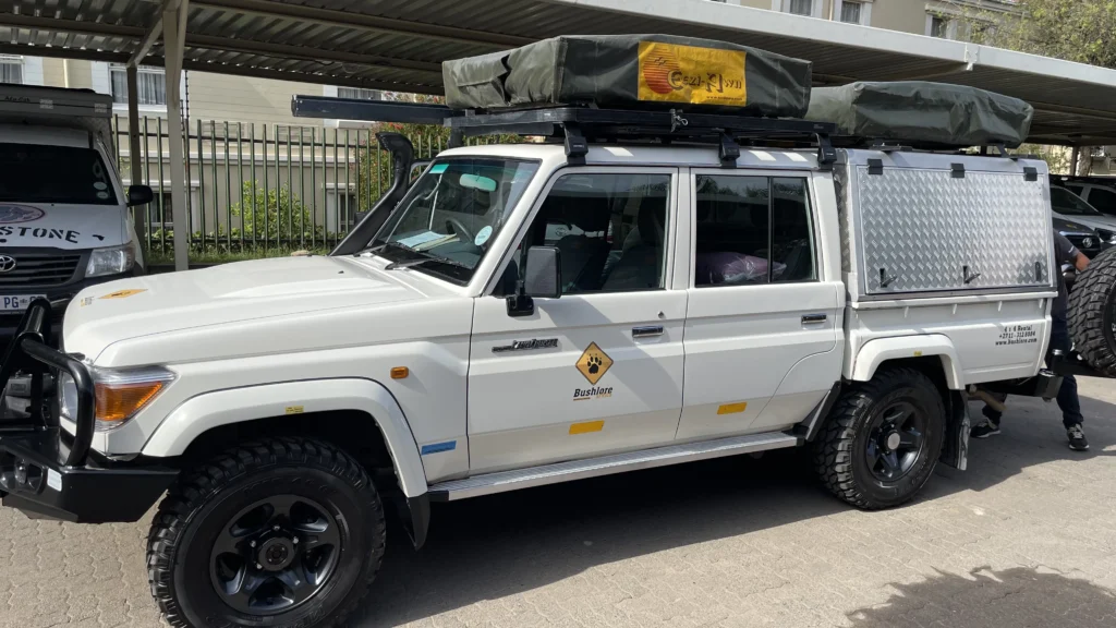 White Bushlore Land Cruiser with rooftop tent and off-road equipment parked under a carport in Johannesburg before an overland trip.